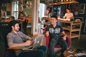 Two man chat happily while working in a laptop.