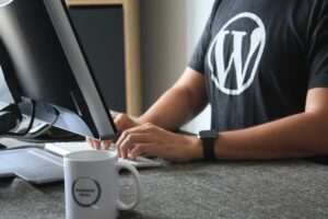 A man is tipying in a keyboard. He wears a WordPress t-shirt